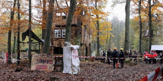 Polizisten neben einem provisorischen Holzhaus Polizisten neben einem provisorischen Holzhaus