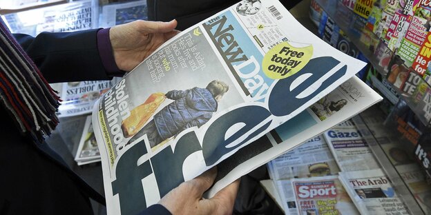 ein Mann hält eine Gratisausgabe einer Zeitung in den Händen ein Mann hält eine Gratisausgabe einer Zeitung in den Händen