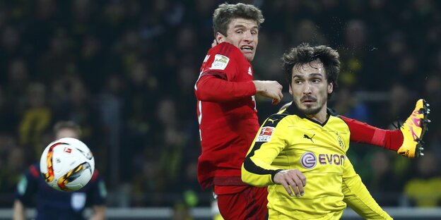 Ein Fußballspieler springt hinter einem anderen hoch. Ein Fußballspieler springt hinter einem anderen hoch.