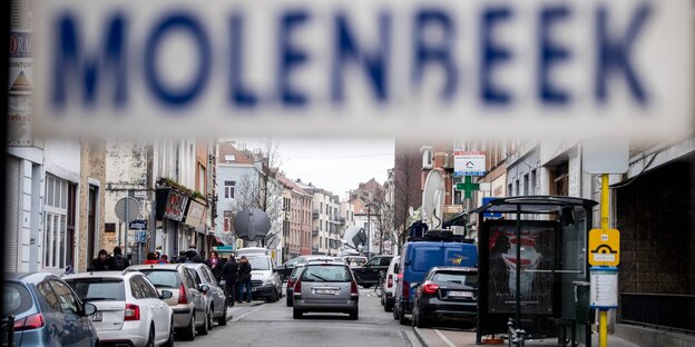 Vorne ein Schild, auf dem Molenbeek steht, im Hintergrund die Stadt