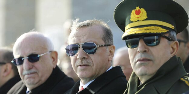 Drei Herren mit Sonnenbrillen und dunklen Anzügen. In der Mitte Präsident Erdoğan Drei Herren mit Sonnenbrillen und dunklen Anzügen. In der Mitte Präsident Erdoğan