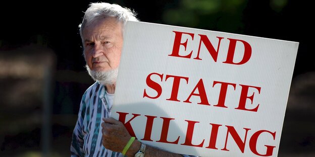 Ein Mann hält ein Schild, auf dem „End State Killing“ steht Ein Mann hält ein Schild, auf dem „End State Killing“ steht