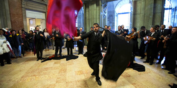Ein Mann wirbelt mit Fahnen, dazu spielt ein Orchester Ein Mann wirbelt mit Fahnen, dazu spielt ein Orchester