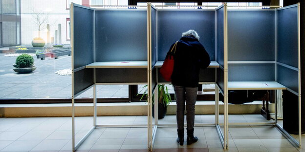 Eine Frau steht an einer Wahlkabine Eine Frau steht an einer Wahlkabine
