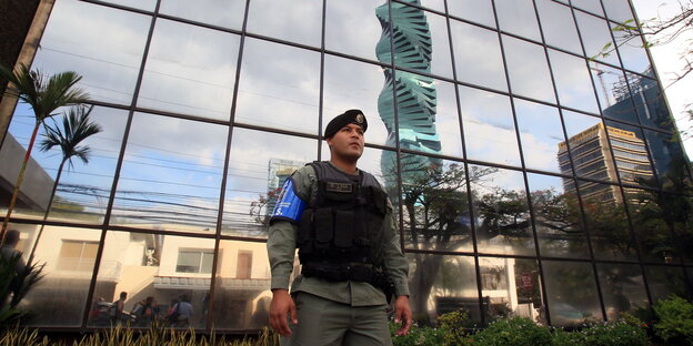 Ein Polizist mit schusssicherer Weste steht vor dem spiegelverglasten Bürogebäude von Mossack Fonseca Ein Polizist mit schusssicherer Weste steht vor dem spiegelverglasten Bürogebäude von Mossack Fonseca
