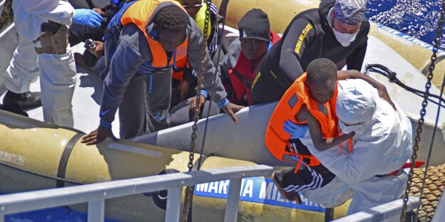 Menschen steigen aus einem Boot auf ein Schiff Menschen steigen aus einem Boot auf ein Schiff
