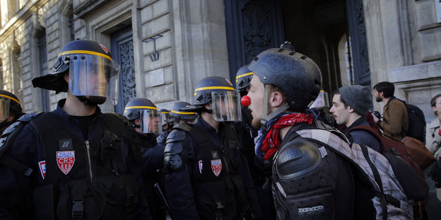 Polizisten mit Helmen und Demonstranten
