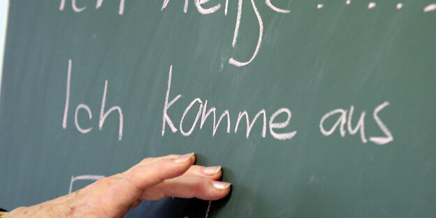 Auf einer Tafel steht "Ich komme aus", eine Hand deutet darauf Auf einer Tafel steht "Ich komme aus", eine Hand deutet darauf