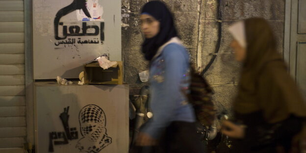 „Stechen, Jerusalem Inftifada“ lautet ein Graffiti an der Wand, zwei Frauen mit Kopftuch laufen vorbei „Stechen, Jerusalem Inftifada“ lautet ein Graffiti an der Wand, zwei Frauen mit Kopftuch laufen vorbei