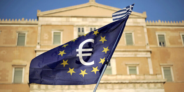 Vor einem großen Gebäude aus dem 19. Jahrhundert weht ein Fahne der Europäischen Union mit einem Euro-Symbol Vor einem großen Gebäude aus dem 19. Jahrhundert weht ein Fahne der Europäischen Union mit einem Euro-Symbol