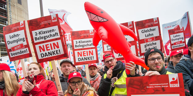 Männer und Frauen mit Trillerpfeifen und Schildern sowie einem Plastikhai Männer und Frauen mit Trillerpfeifen und Schildern sowie einem Plastikhai