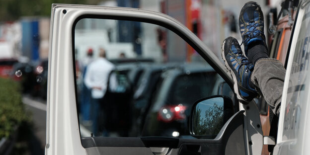 Ein Lkw-Fahrer streckt seine Füße durch die Fensterscheibe seiner offenen Fahrertür. Ein Lkw-Fahrer streckt seine Füße durch die Fensterscheibe seiner offenen Fahrertür.