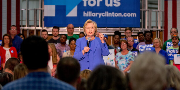 Hillary Clinton steht vor einem Saal voller Leute Hillary Clinton steht vor einem Saal voller Leute