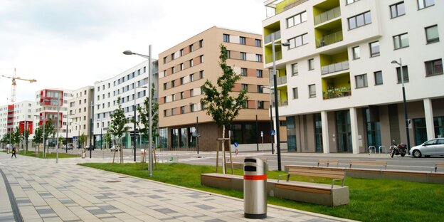 Ein sauberer Bürgersteig mit Müllkorb, im Hintergrund neue Häuser Ein sauberer Bürgersteig mit Müllkorb, im Hintergrund neue Häuser