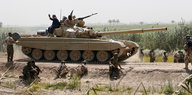 Ein Panzer und bewaffnet Uniformierte auf einem Sandweg