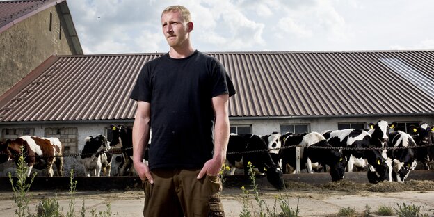 Ein junger Bauer vor einem Stall mit Kühen Ein junger Bauer vor einem Stall mit Kühen