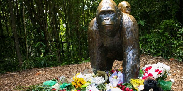 Vor einer Bronzestatue liegen Blumen