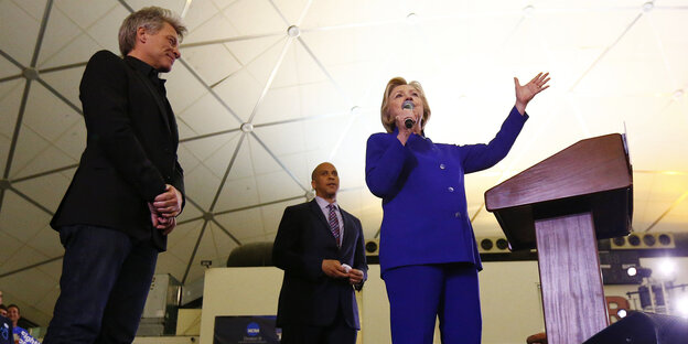Jon Bon Jovi, Hillary Clinton und ein Senator von New Jersey stehen auf einer Wahlkampfbühne Jon Bon Jovi, Hillary Clinton und ein Senator von New Jersey stehen auf einer Wahlkampfbühne
