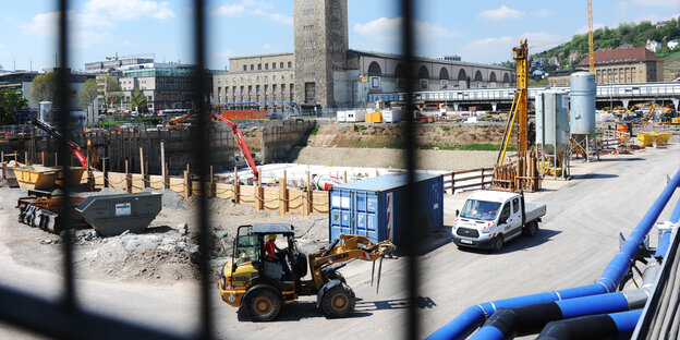 Blick auf die Baustelle von S21, im Vordergrund ein Bagger, im Hintergrund das alte Bahnhofsgebäude