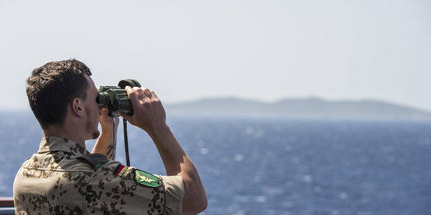 Soldat mit Feldstecher vor Meer und Küste Soldat mit Feldstecher vor Meer und Küste