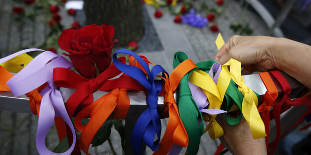 Bänder in den farben des Regenbogens werden um ein Geländer gebunden