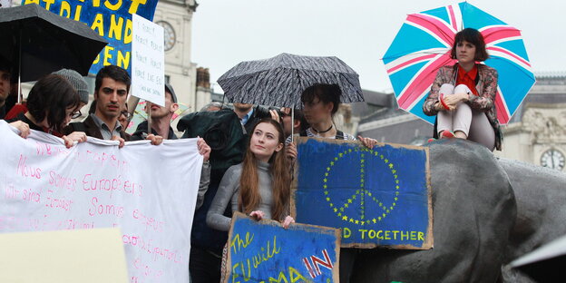 Menschen halten Schilder, die die Europafahne zeigen