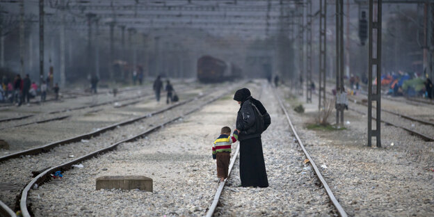 Eine Frau und ein Kind laufen über Bahngleise in Idomeni Eine Frau und ein Kind laufen über Bahngleise in Idomeni