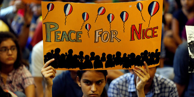 Eine Frau hält ein Schild mit der Aufschrift: Peace for Nice Eine Frau hält ein Schild mit der Aufschrift: Peace for Nice