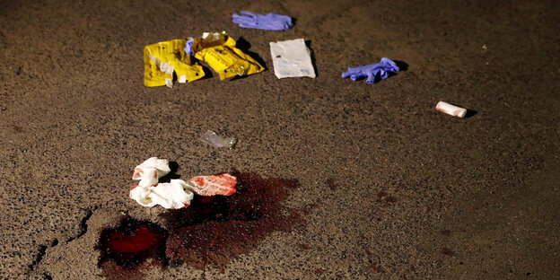 Eine Blutlache, daneben violette Gummihandschuhe und Mullbinden Eine Blutlache, daneben violette Gummihandschuhe und Mullbinden
