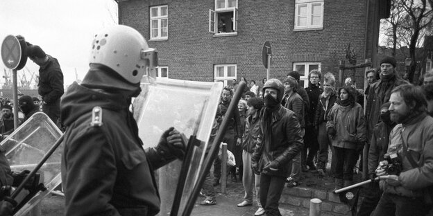 Polizisten mit Schilden und Schlagstöcken stehen Demonstranten gegenüber Polizisten mit Schilden und Schlagstöcken stehen Demonstranten gegenüber