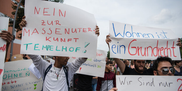 Flüchtlinge halten am 11.07.2016 bei einer Demonstration in Berlin-Neukölln Schilder mit der Aufschrift "Nein zur Massenunterkunft Tempelhof" und "Wohnen ist ein Grundrecht". Mit der Aktion protestieren die Flüchtlinge gegen ihre geplante Unterbringung in Flüchtlinge halten am 11.07.2016 bei einer Demonstration in Berlin-Neukölln Schilder mit der Aufschrift "Nein zur Massenunterkunft Tempelhof" und "Wohnen ist ein Grundrecht". Mit der Aktion protestieren die Flüchtlinge gegen ihre geplante Unterbringung in