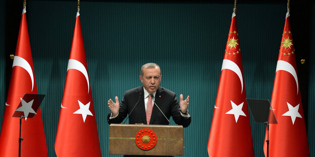 Mann in Anzug an Rednerpult, daneben türkische Fahnen. Es ist der türkische Präsident Erdogan Mann in Anzug an Rednerpult, daneben türkische Fahnen. Es ist der türkische Präsident Erdogan