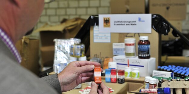 Ein Zollbeamter hält ein Fläschchen mit Testosteron in der Hand Ein Zollbeamter hält ein Fläschchen mit Testosteron in der Hand
