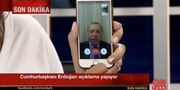 Der türkische Präsident Erdogan spricht über die Facetime-Funktion zur Bevölkerung. Eine Moderatorin von CNN Türk hält das Handy mit seinem Bild in die Kamera Der türkische Präsident Erdogan spricht über die Facetime-Funktion zur Bevölkerung. Eine Moderatorin von CNN Türk hält das Handy mit seinem Bild in die Kamera