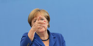 Angela Merkel vor einer blauen Wand, sie zeigt nach vorne