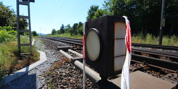 Ein ausgeblichenes Absperrband hängt an Bahnschienen Ein ausgeblichenes Absperrband hängt an Bahnschienen