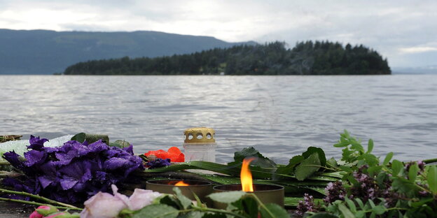 Blumen und Kerzen, dahinter Wasserfläche mit einer Insel Blumen und Kerzen, dahinter Wasserfläche mit einer Insel