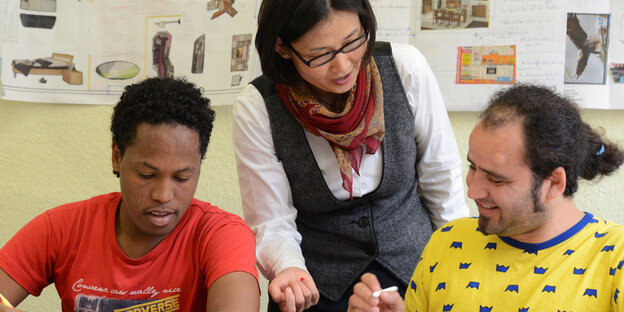 Eine Lehrerin spricht beim Deutsch-Unterricht im Integrationskurs mit zwei Schülern