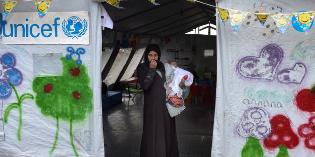 Eine Flüchtlingsfrau steht mit ihrem Baby in einem Zelt des UN-Kinderhilfswerkes Unicef an der Grenze zu Griechenland