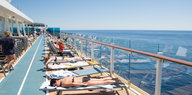 Menschen liegen auf einem Kreuzfahrtschiff auf Sonnenliegen