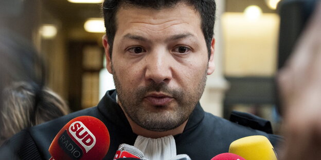 Ein Mann spricht in Mikrofone. Es ist Arié Alimi Ein Mann spricht in Mikrofone. Es ist Arié Alimi