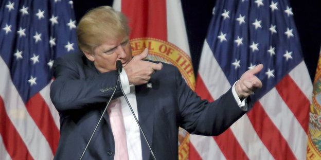 Donald Trump tut so, als würde er mit einem Gewehr schießen