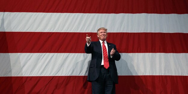 Donald Trump vor einer riesigen US-Fahne Donald Trump vor einer riesigen US-Fahne