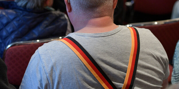 Rücken eines Mannes, der Hosenträger in schwarz-rot-gold trägt Rücken eines Mannes, der Hosenträger in schwarz-rot-gold trägt