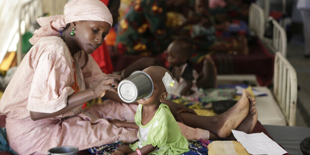 Eine Mutter füttert ihr Kind in einem Hilfszentrum in Maiduguri in Nigeria Eine Mutter füttert ihr Kind in einem Hilfszentrum in Maiduguri in Nigeria