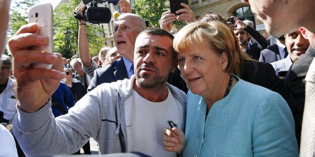 Ein Migrant macht ein Selfie mit Angela Merkel