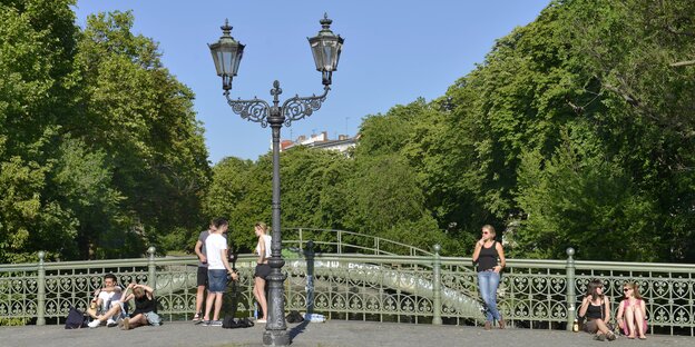 Menschen lehnen oder sitzen am Brückengeländer und genießen das schöne Wetter Menschen lehnen oder sitzen am Brückengeländer und genießen das schöne Wetter