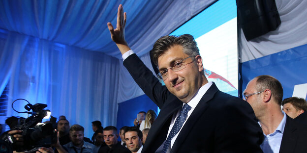 Ein Politiker in einer Art Festzelt, er hebt den Arm und schaut in die Kamera Ein Politiker in einer Art Festzelt, er hebt den Arm und schaut in die Kamera