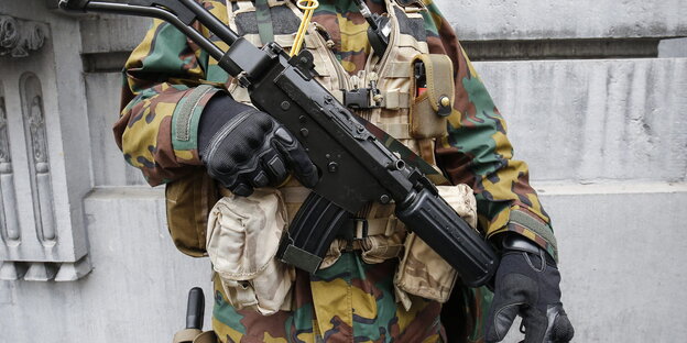 Ein Mensch in Uniform hält sein Gewehr vor der Brust Ein Mensch in Uniform hält sein Gewehr vor der Brust