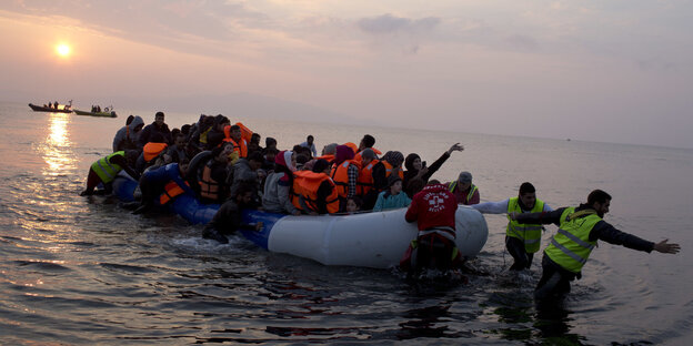 Ein sehr volles Boot wird von Helfern an Land gezogen